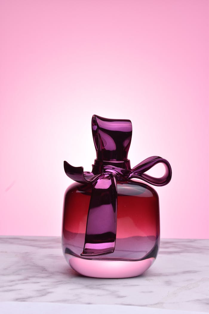 Luxury perfume bottle in vibrant pink glass on marble, perfect for fashion and beauty themes.